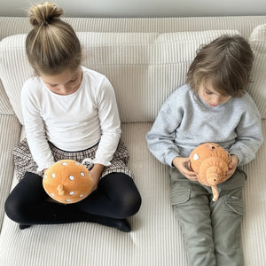 Zwei Kinder sitzen auf einem Sofa. Beide halten jeweils einen Lenabie Plüschcharakter in den Händen und schauen diese aufmerksam an. Die Kinder lauschen den individuellen Hörspielen, die jedes Lenabie mitbringt und von Eltern bequem über die Lenabo App auswählen und steuern.